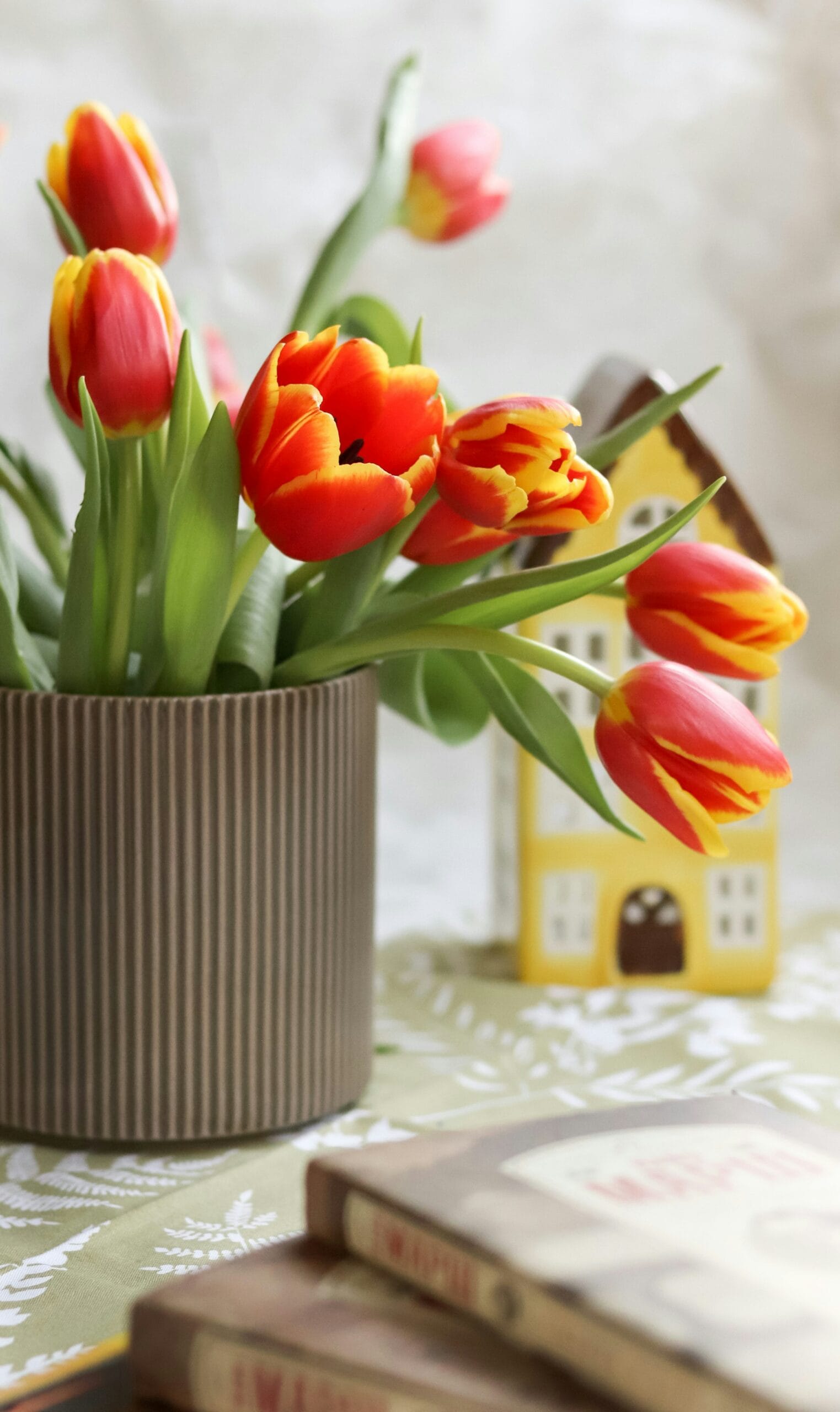 A well-maintained home with spring flowers blooming in the front yard and a for-sale sign on the lawn