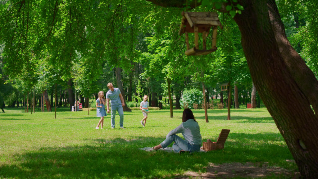 Cheerful family leisure in summer park tranquil mother watching father standing with k SBI
