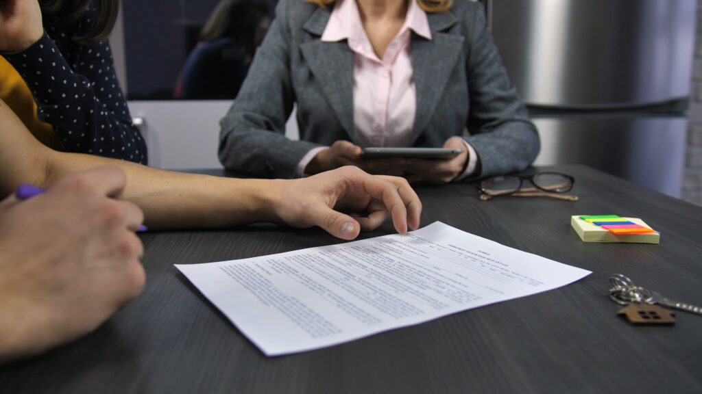 Midsection of realtor and family couple sitting at table husbands hands reading house SBI